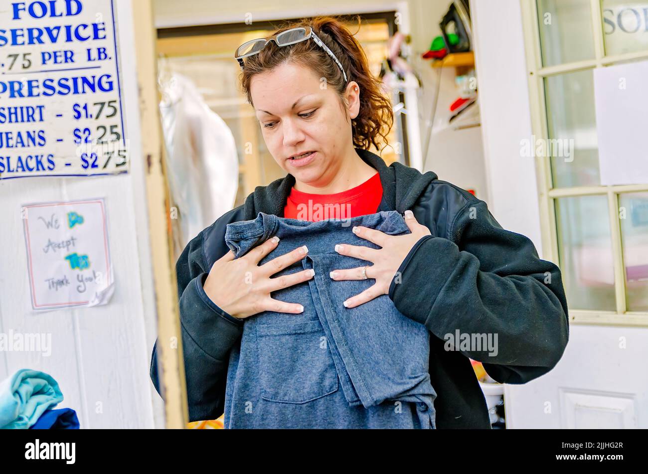 A woman folds laundry at a laundromat, Feb. 23, 2013, in Columbus, Mississippi. The job pays minimum wage. Stock Photo