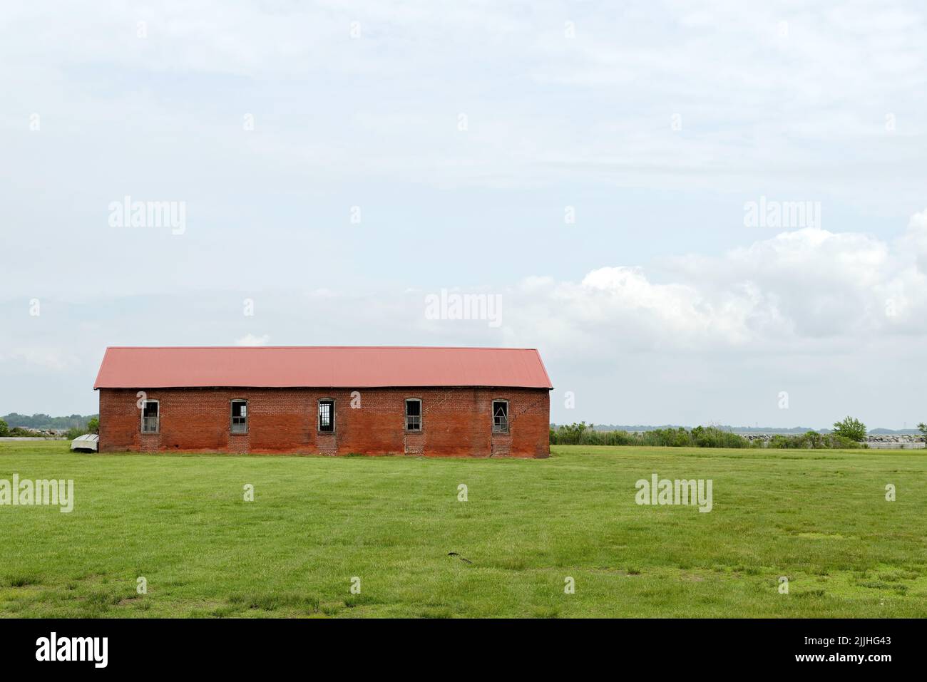 An old, empty red barn stands in a field on Pea Patch Island, Delaware, part of the Fort Delaware complex. Stock Photo