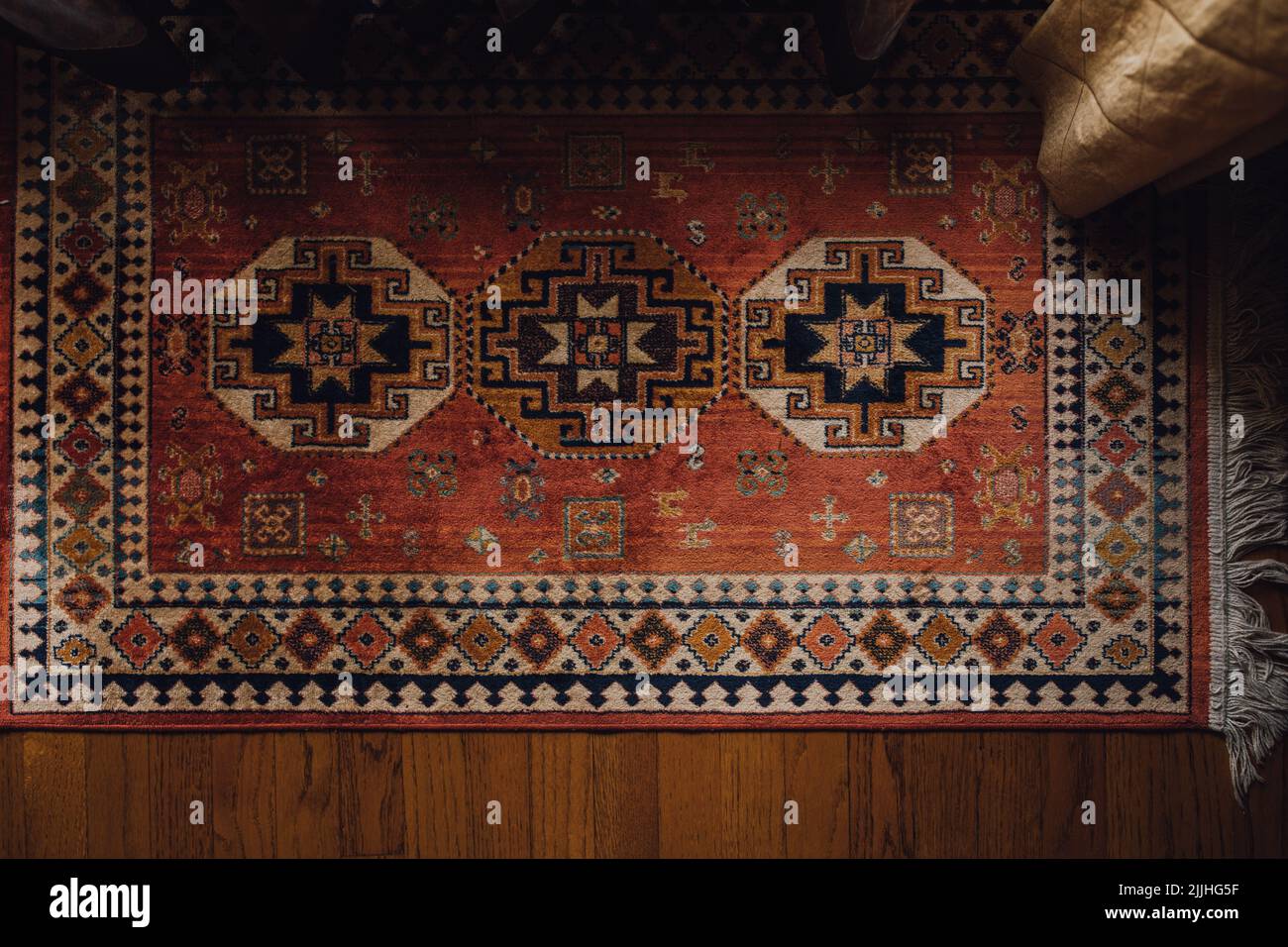 directly above view of small patterned middle eastern rug on wood floor with gold curtain Stock Photo