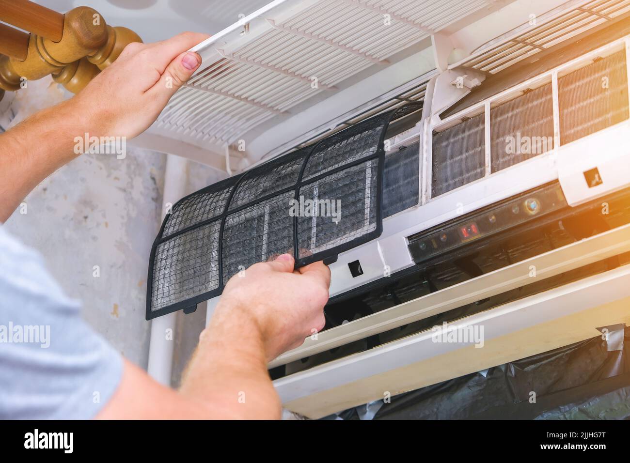 The man takes out filters from the air conditioner for cleaning. Split