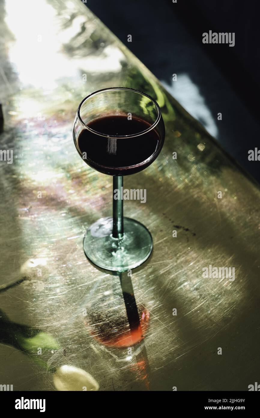 https://c8.alamy.com/comp/2JJHG9Y/red-wine-in-green-stem-french-luminarc-wine-glass-on-golden-brass-table-2JJHG9Y.jpg