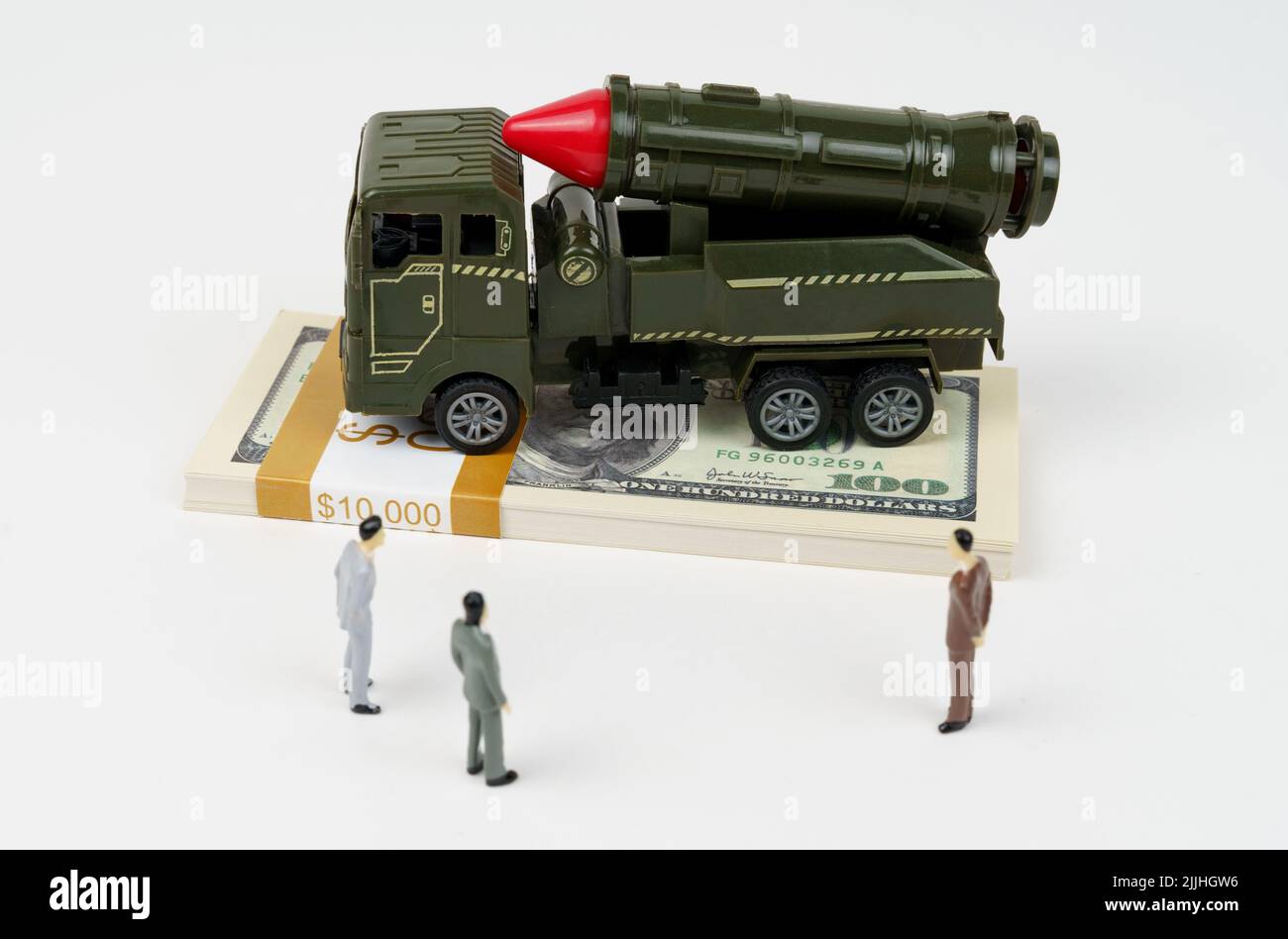 The concept of the military budget. On the dollars is a toy military vehicle, next to the figures of businessmen. Stock Photo