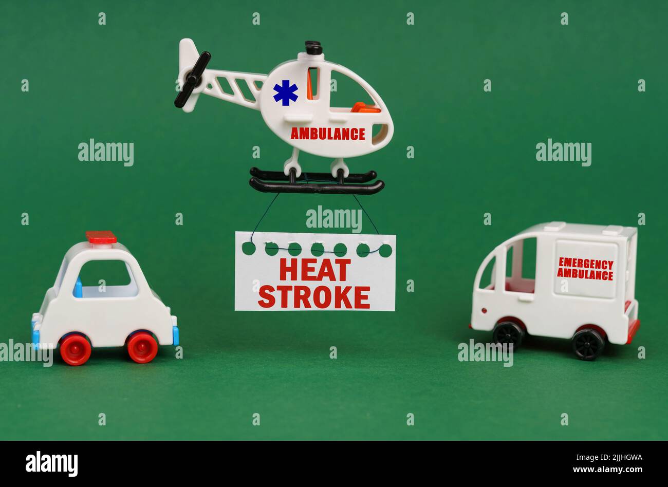 Medical concept. On a green surface, cars and an ambulance helicopter with a sign - HEAT STROKE Stock Photo