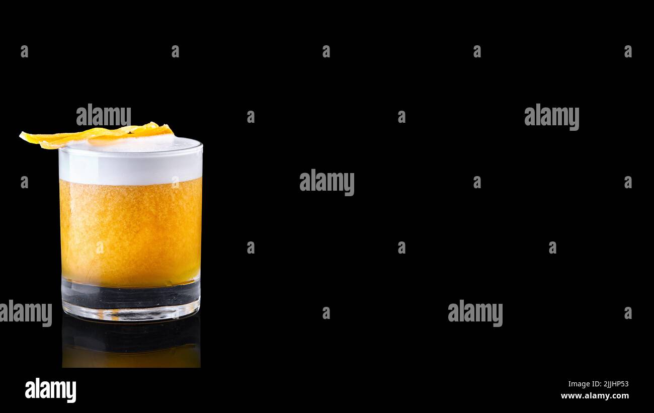 whiskey sour cocktail served on the rocks isolated on a black background garnished with an orange slice Stock Photo