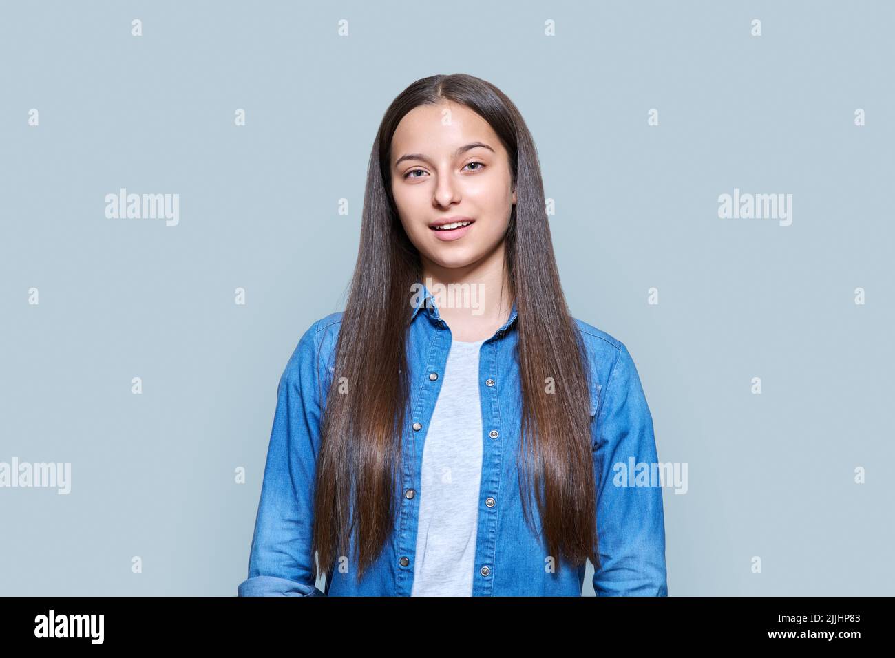 Portrait of teenage girl looking at camera on grey background Stock ...