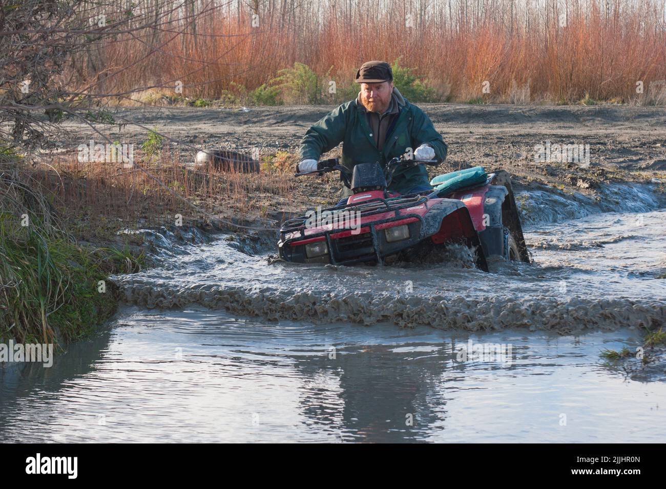 A Look at life in New Zealand: practising river crossings and mud bogging on the Quadbike: often the only way to reach the best fishing spots. Stock Photo