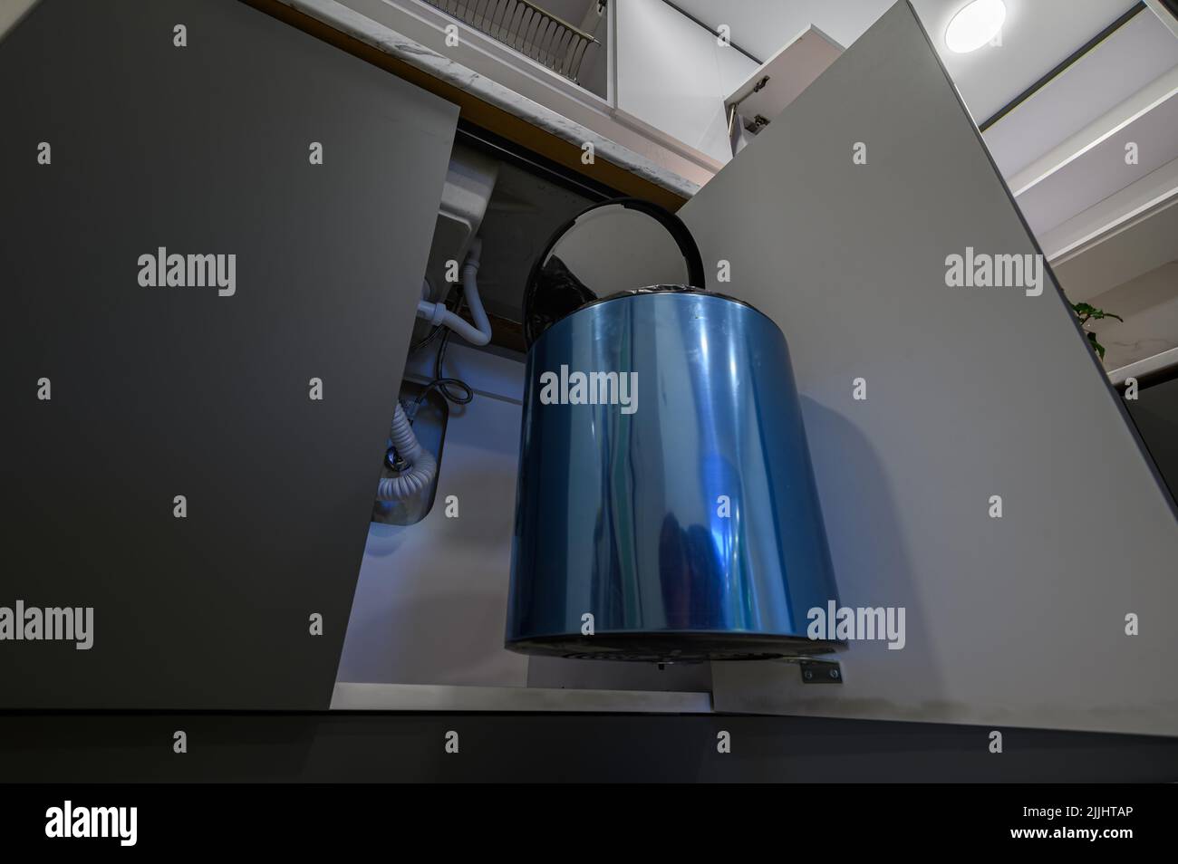 Trash can inside the trendy dark grey and white kitchen furniture Stock