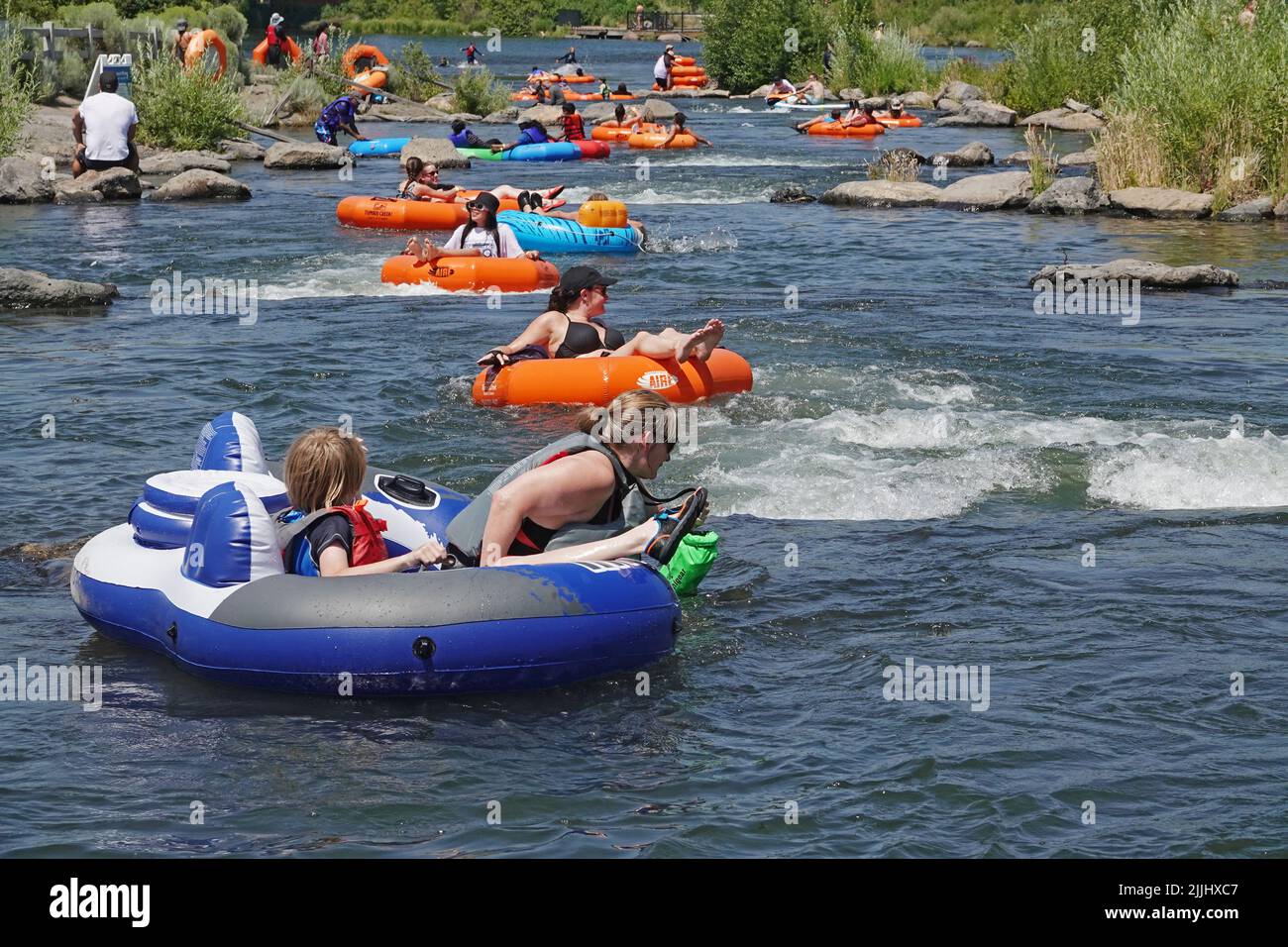 Beating the heat in the American Pacific Northwest. The state of Oregon and the Pacific Northwest in general is undergoing another major heatwave with temperatures reaching 100 degrees farenheit plus during the afternoons. Floating the river is a popular way to cool off. This is the Deschutes River in Bend, Oregon. Stock Photo