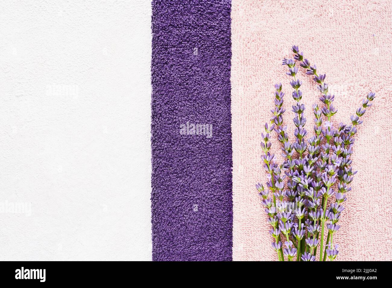 Lavender flowers and fluffy towels on the light background. SPA, wellness well-being, body care concept. Copy space for text, top view Stock Photo