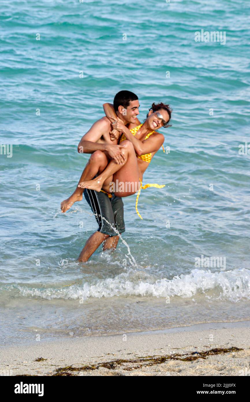 Miami Beach Florida,Atlantic Ocean Shore seashore,Hispanic couple adult adults man men male,woman women female lady,playing frolic near surf,public Stock Photo