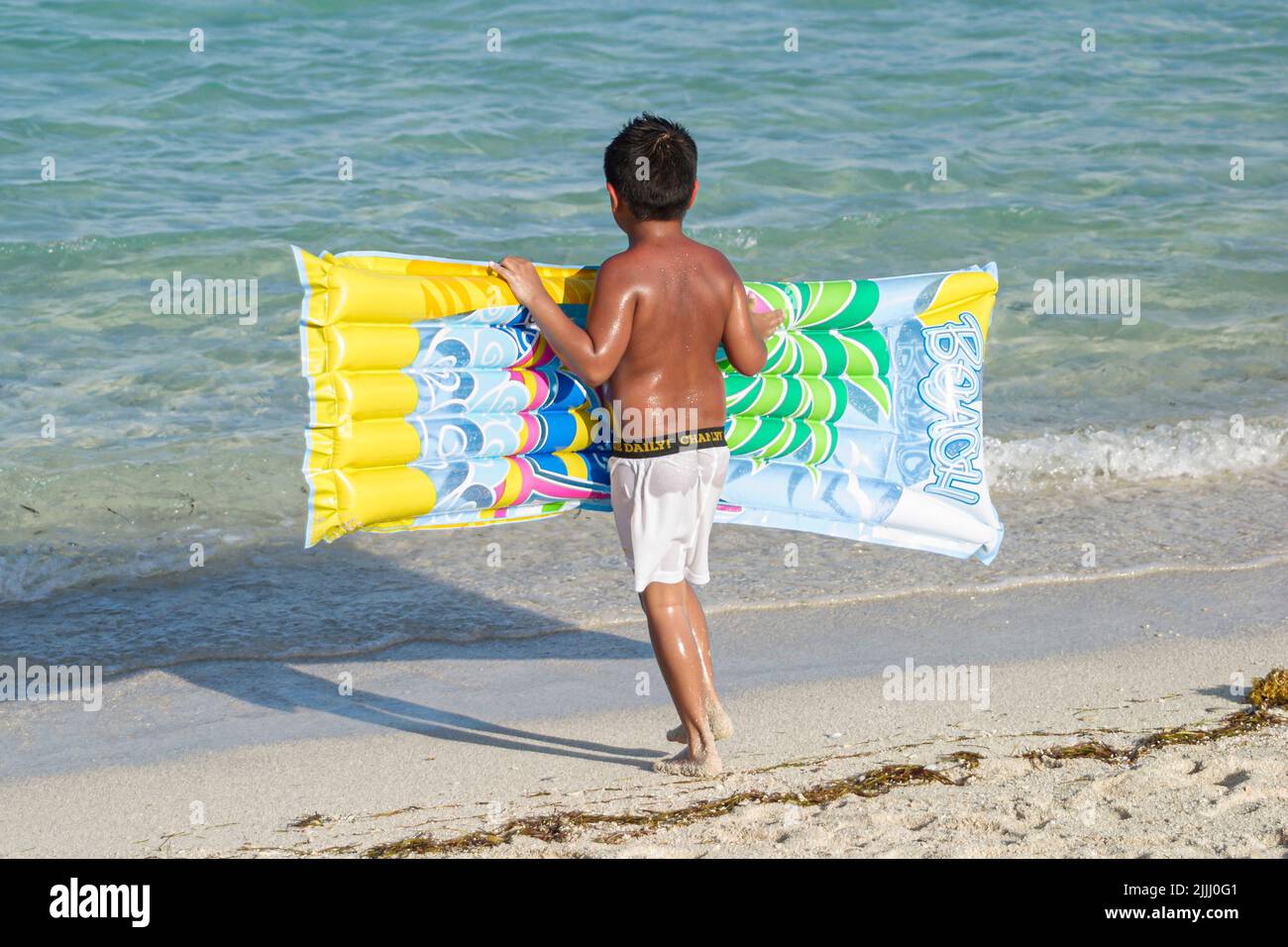 Miami Beach Florida,Atlantic Ocean Shore shoreline coast coastline seashore,Hispanic boy inflatable raft,edge of water surf Stock Photo