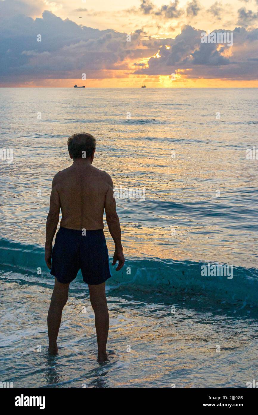 Miami Beach Florida,Atlantic Ocean Shore coast seashore,senior seniors citizen Hispanic adult adults man men male,bathing suit surf at sunrise Stock Photo