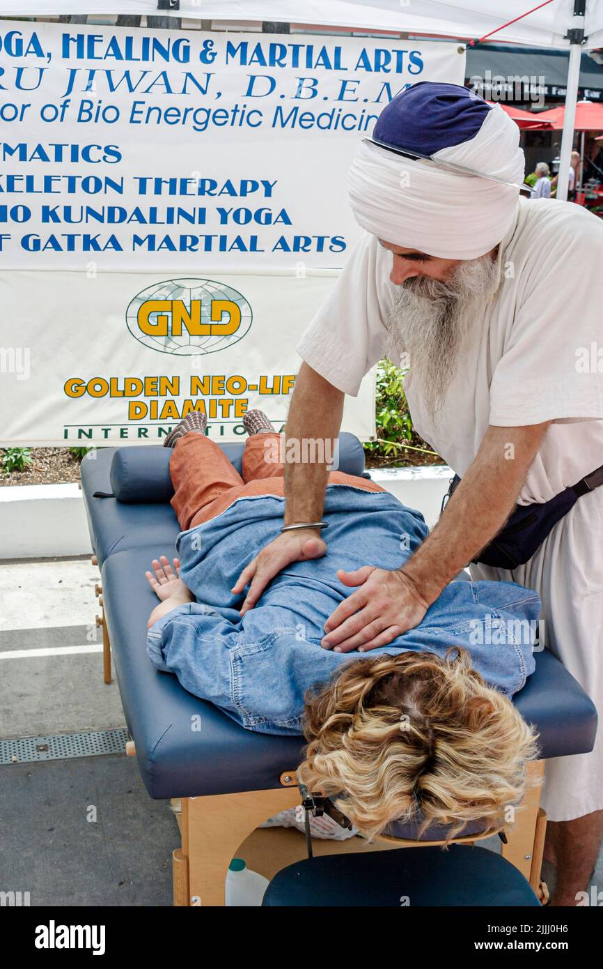 Miami Beach Florida,Lincoln Road pedestrian mall man men male,Asian Indian Hindu outfit offering giving performing massage,woman female receiving Stock Photo