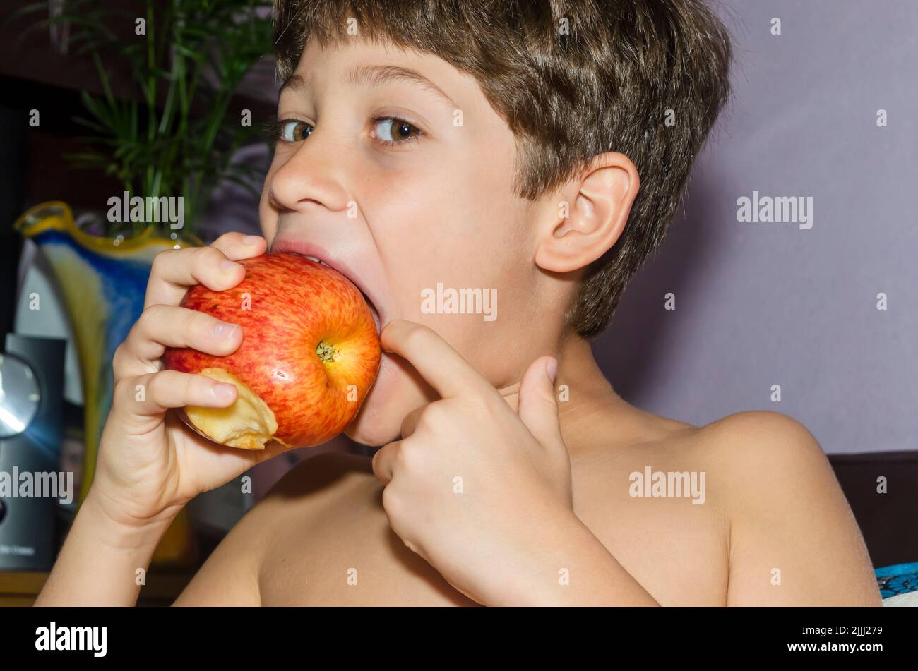 Child eating red apple at home. Salvador, Bahia, Brazil. Stock Photo
