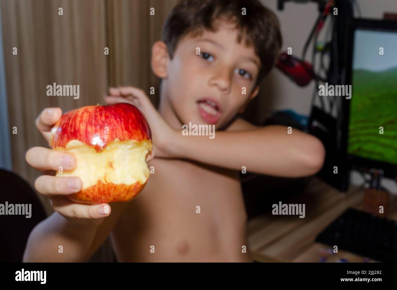Child eating red apple at home. Salvador, Bahia, Brazil. Stock Photo