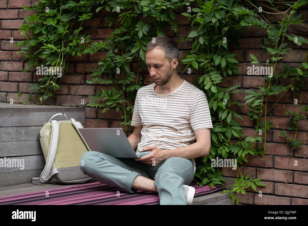 Concentrated young man freelance web developer working remotely at outdoor work environment Stock Photo