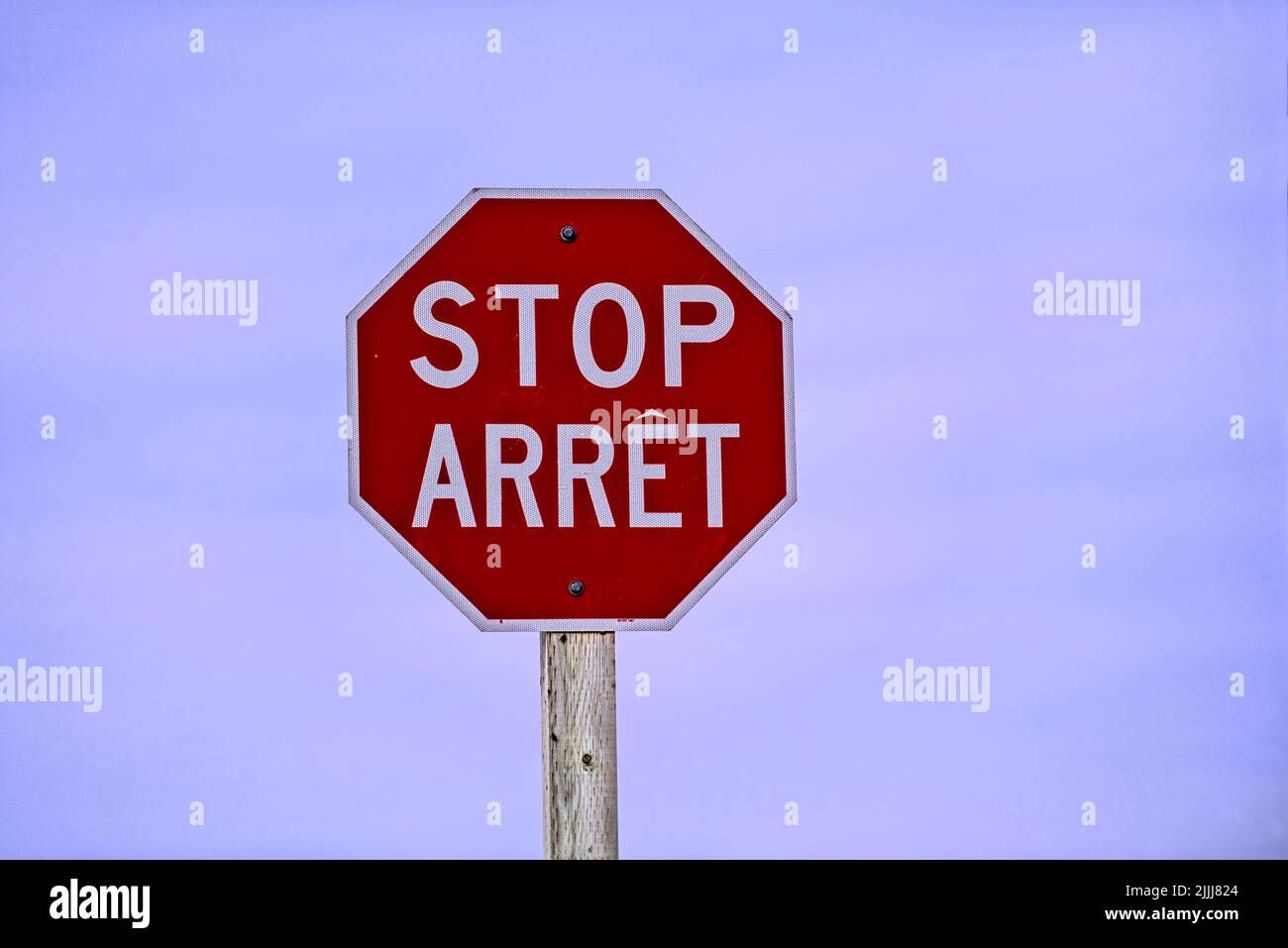 A horizontal image of a red bilingual stop sign located in rural New Brunswick Canada Stock Photo