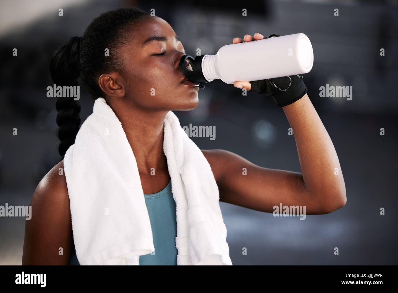Exercise regularly and drink plenty of water. a fit young woman drinking water while at the gym. Stock Photo