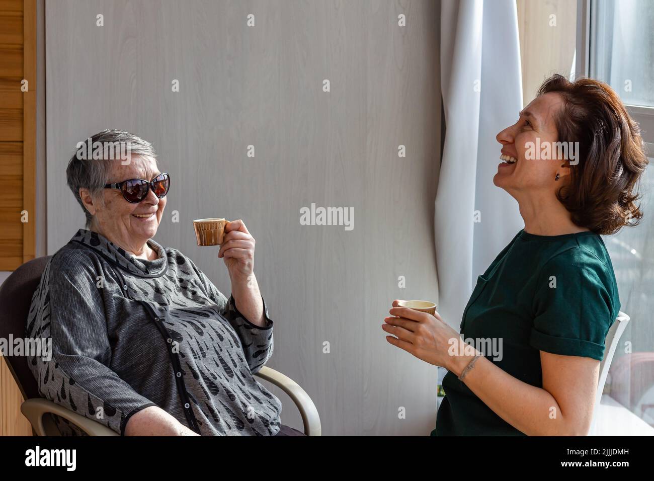 Mother and millennial daughter spend time together on country house veranda, chatting. The concept of warm trusting relationships, selective focus Stock Photo