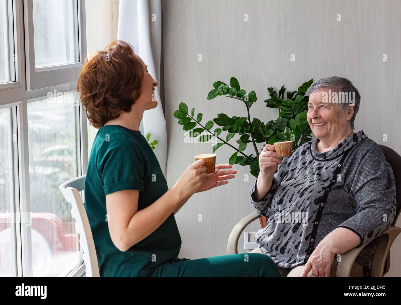 Mother and daughter spend time together on country house veranda, drinks coffee. concept of warm trusting relationships, selective focus Stock Photo