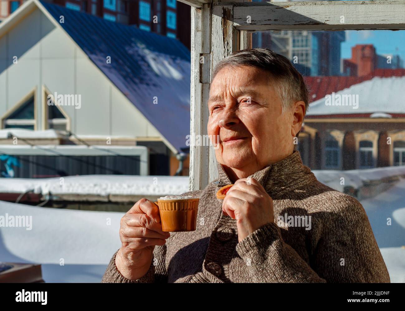 Smiling mature female in warm clothes having cup of hot tea coffee on terrace. Day of Older Persons. Selective Focus. lifestyle concept happy. Stock Photo