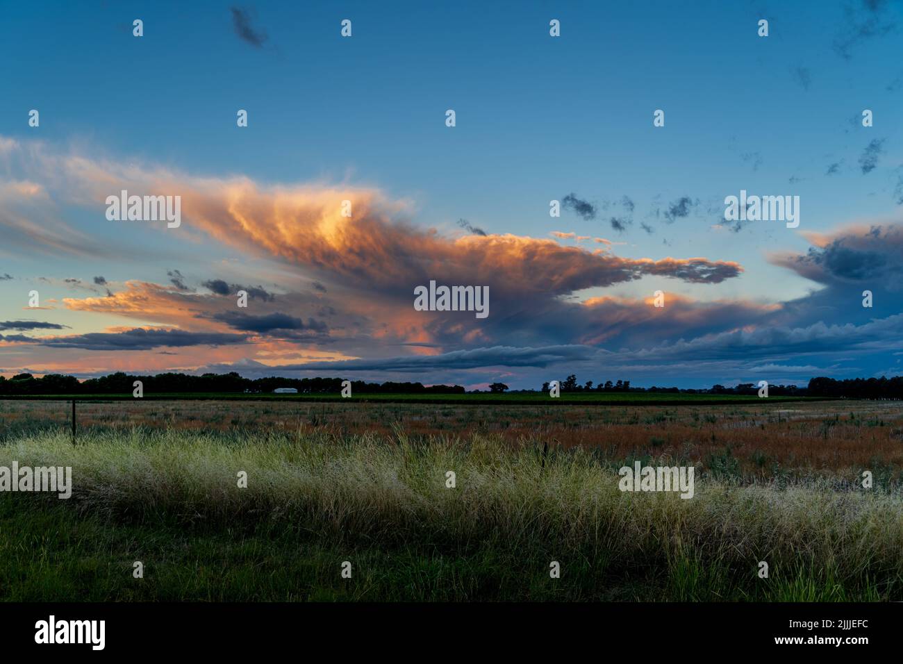A beautiful scene of sunset cloudy sky over green grass fields Stock ...