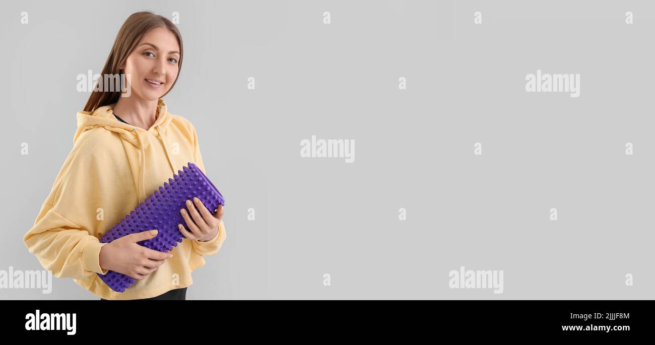 Young woman with foam roller on light background with space for text ...