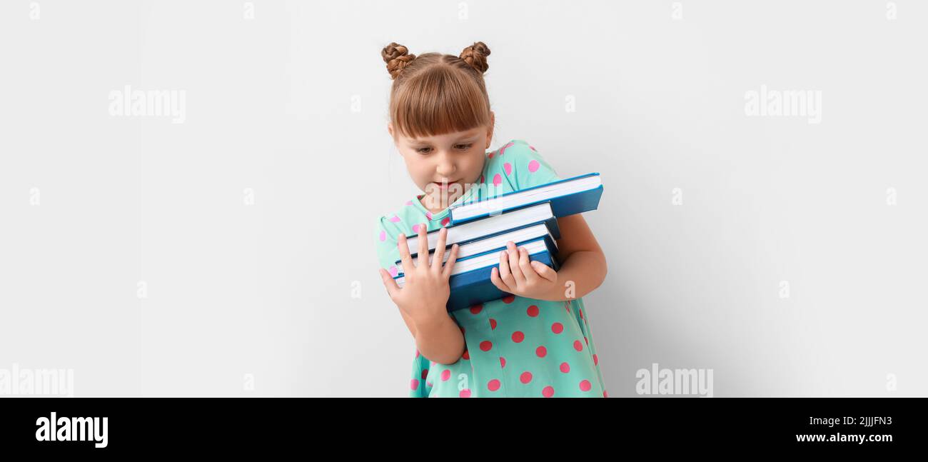 Cute little schoolgirl with books on light background Stock Photo - Alamy