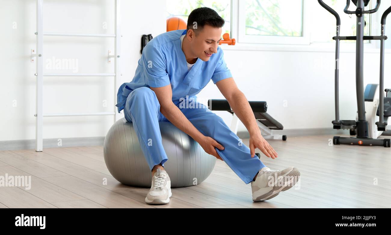 Male physiotherapist demonstrating exercise with fitball in