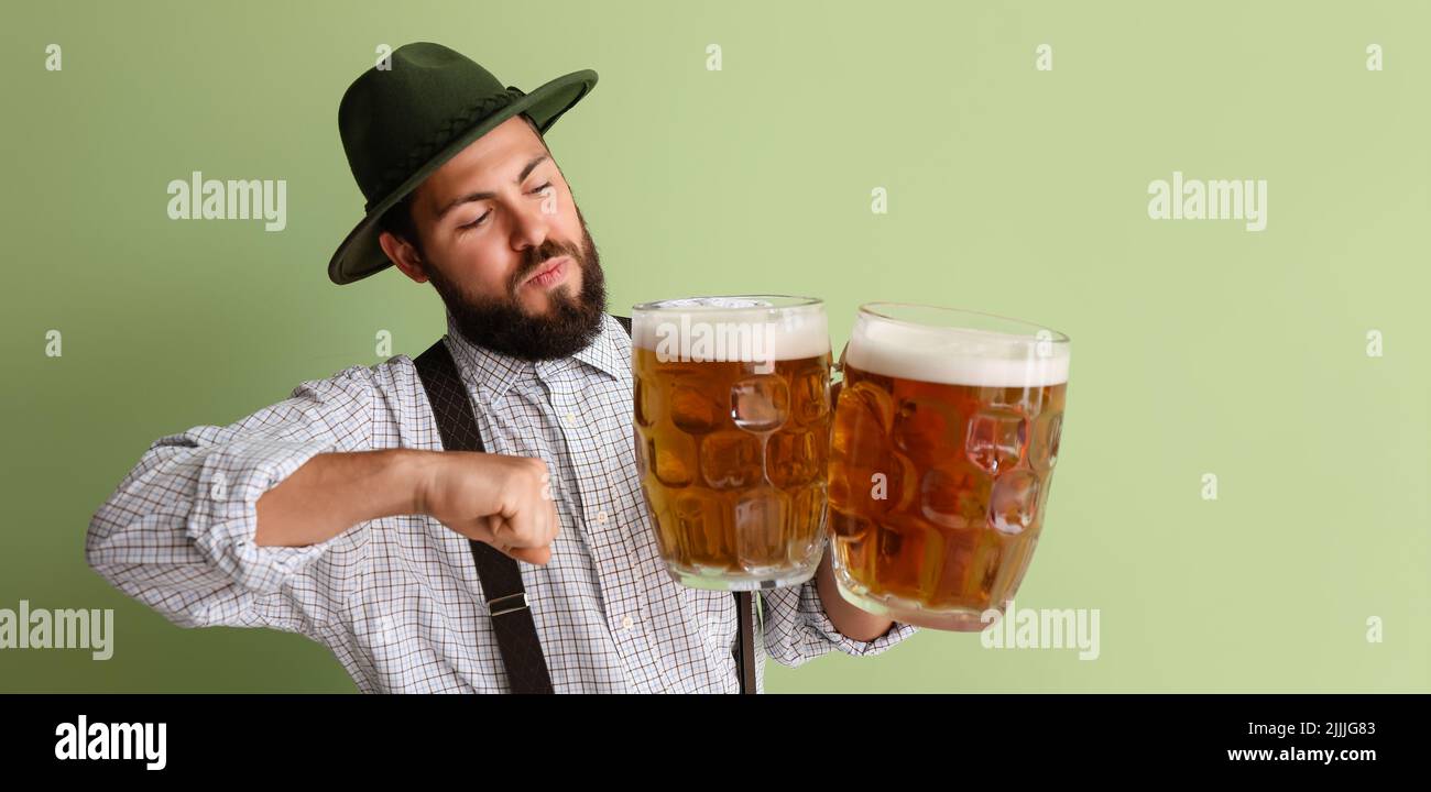 Man in traditional German clothes and with beer on green background