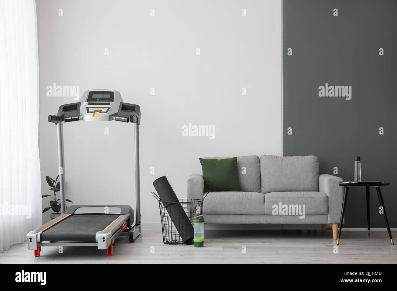 Interior of light living room with treadmill and sofa Stock Photo Alamy