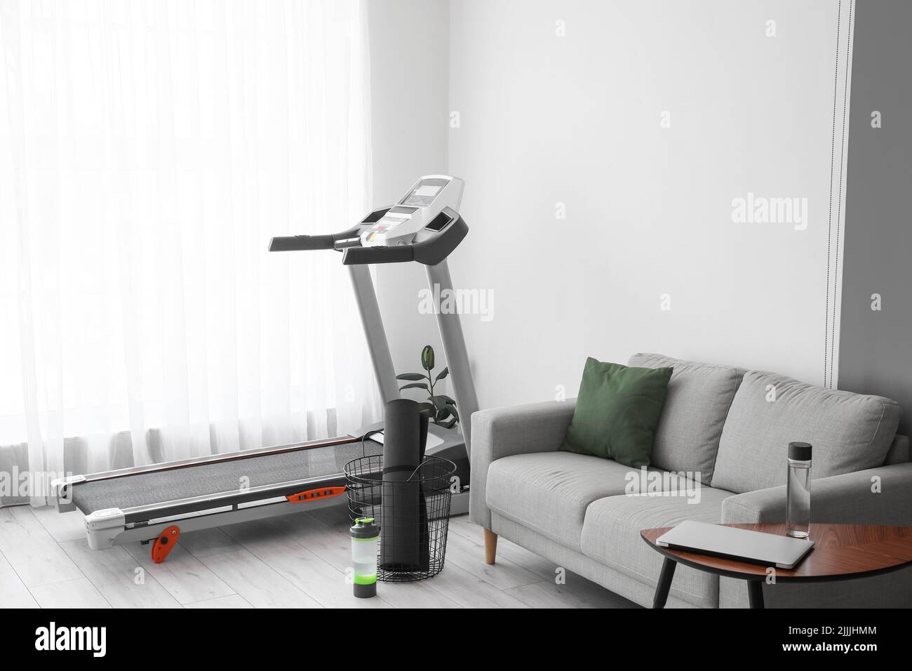 Interior of light living room with treadmill and sofa Stock Photo Alamy