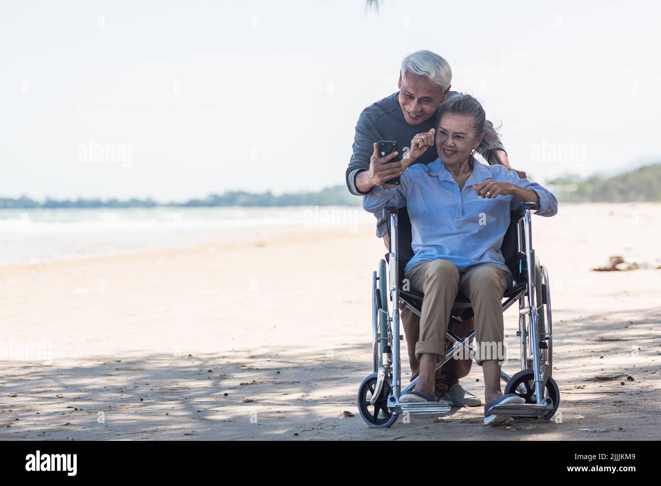 Happy Asian elderly woman sitting in wheelchair and husband is a ...