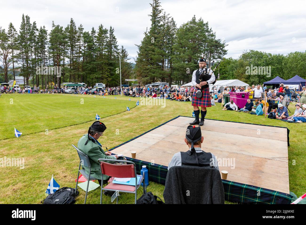 Highland games being held in Tomintoul Moray on 17 July 2022, Scotland, man playing the bagpipes before the two person judging panel,Scotland,UK Stock Photo