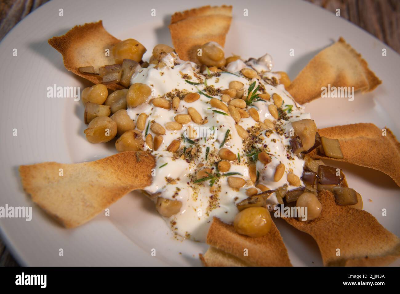 Oriental recipe aubergine and chickpea fatteh, pita, Greek yogurt, roasted pine nuts, zaatar Stock Photo