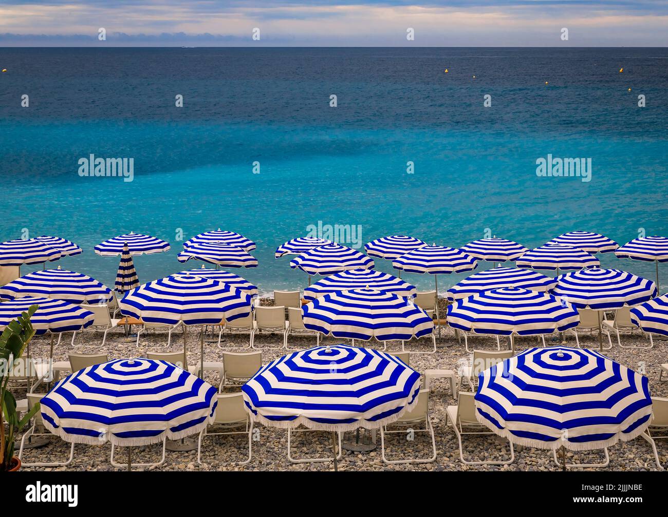 Pebble beach along Promenade des Anglais with beach umbrellas and chairs  with the turquoise water of the Mediterranean Sea in Nice, Cote d'Azur  France Stock Photo - Alamy