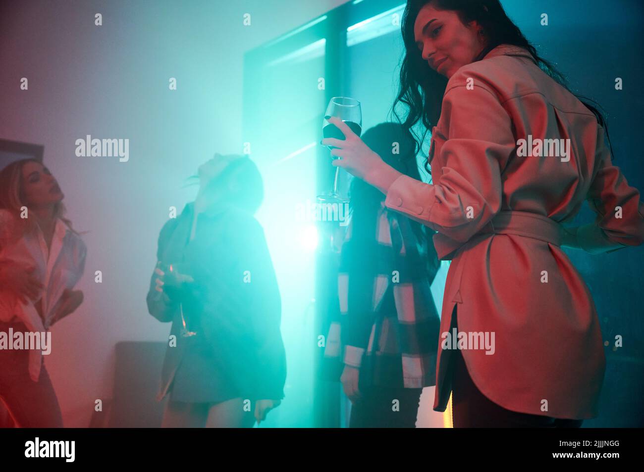 Young women having party inside contemporary barn house at night. Stock Photo