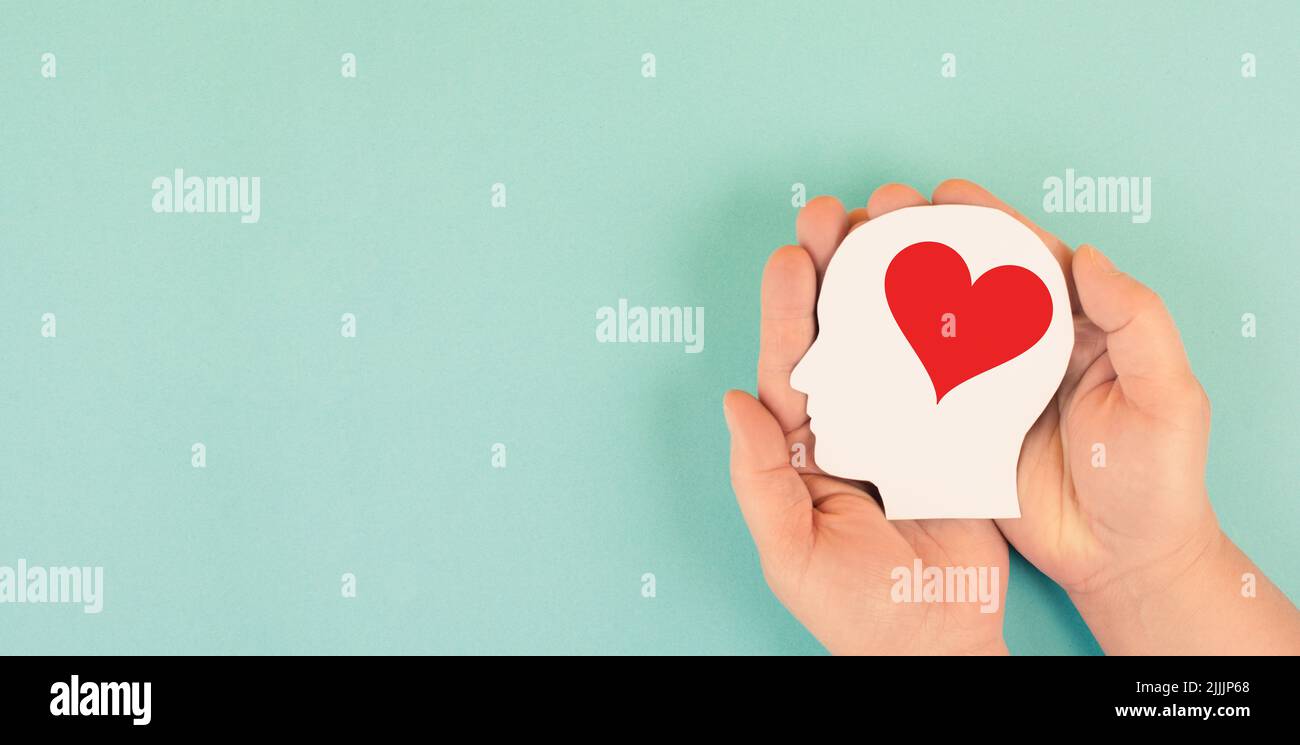 Holding a head with a red heart in the hands, symbol of love and positive emotion, charity and support Stock Photo
