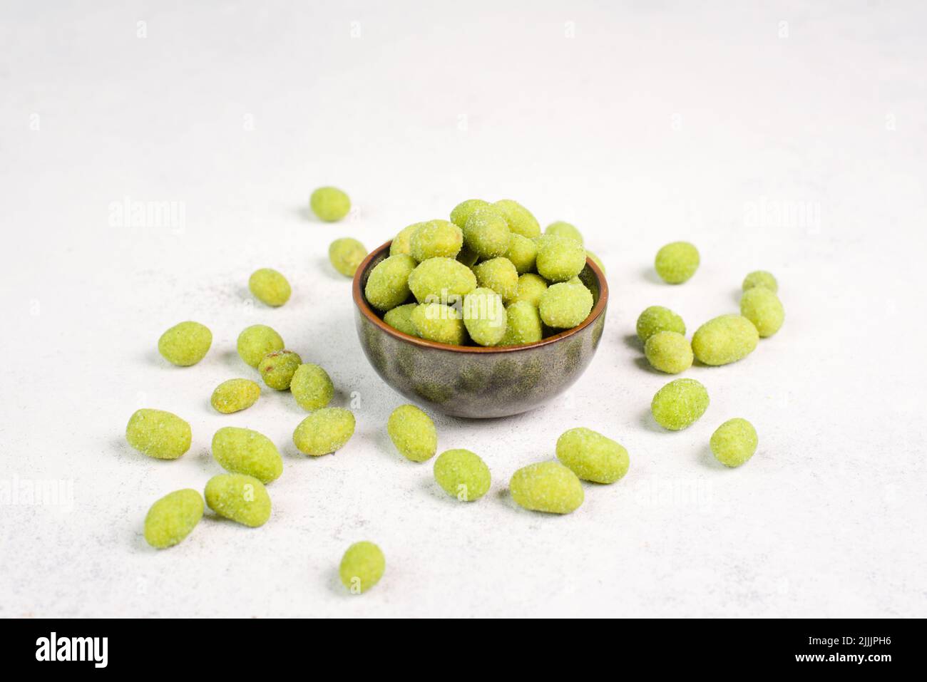 Pile of green wasabi coated peanuts in a bowl, spicy snack, oriental