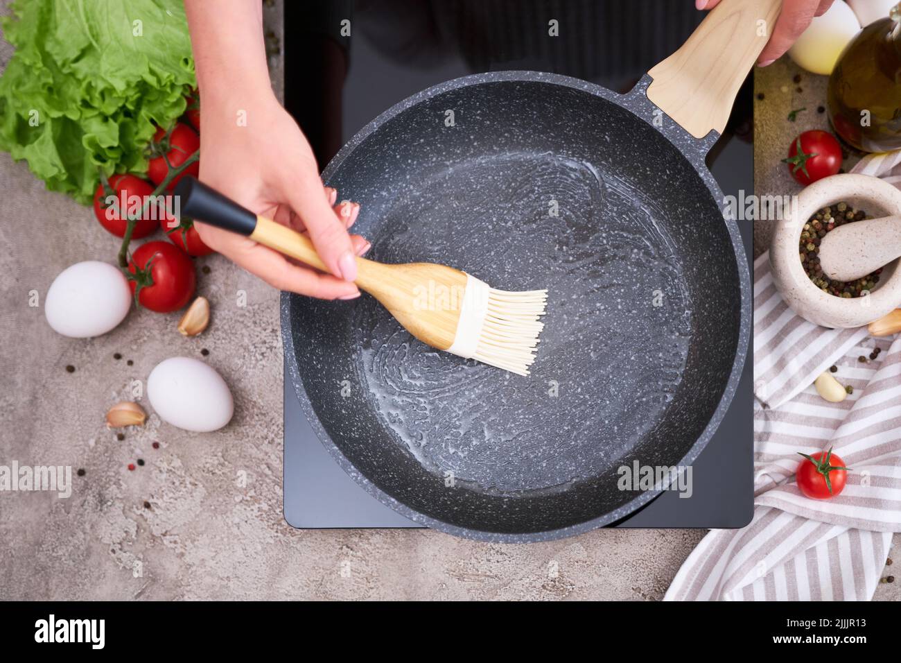 Woman smear olive oil on frying pan with silicone brush at domestic