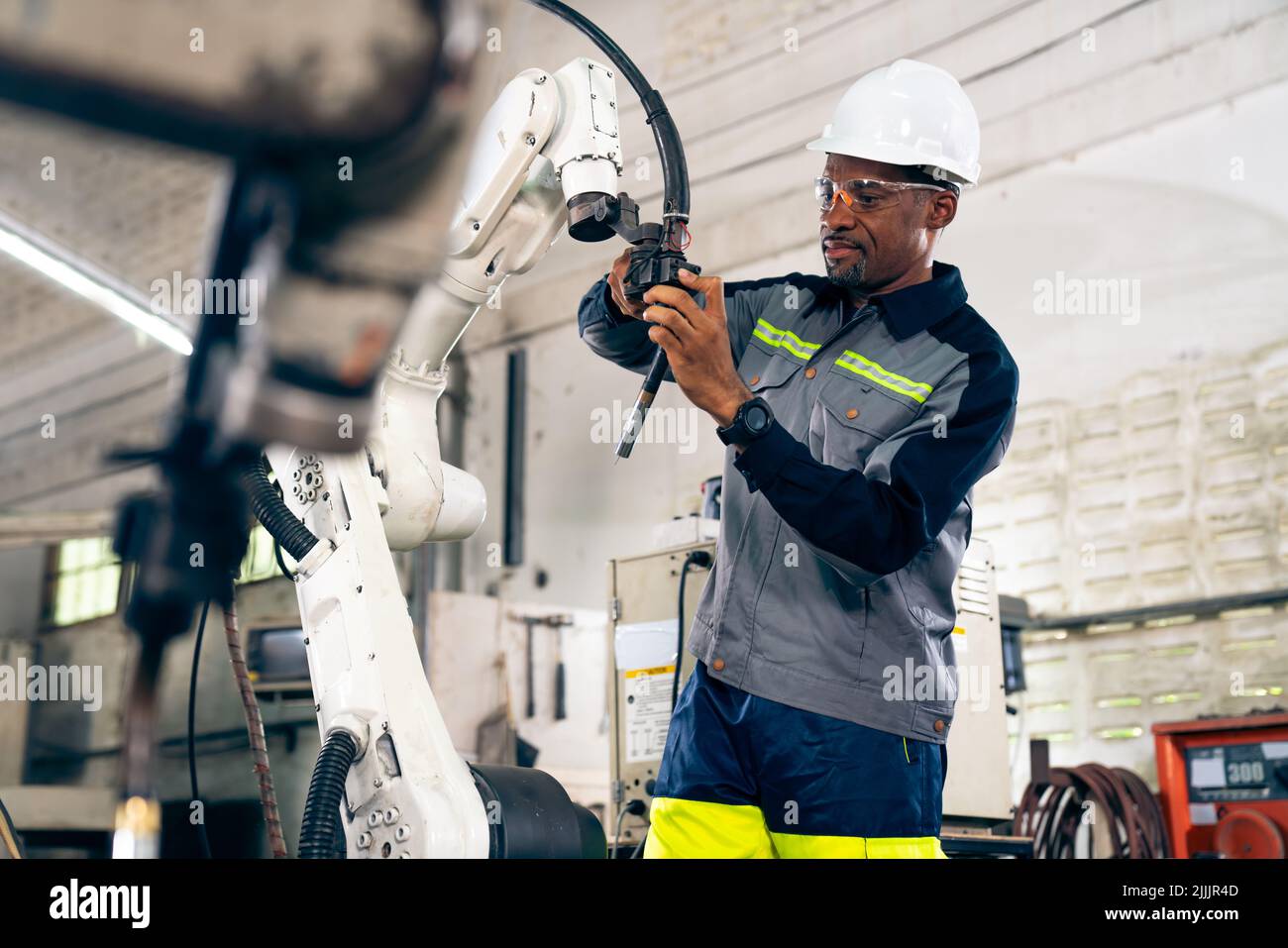 African American factory worker working with adept robotic arm in a