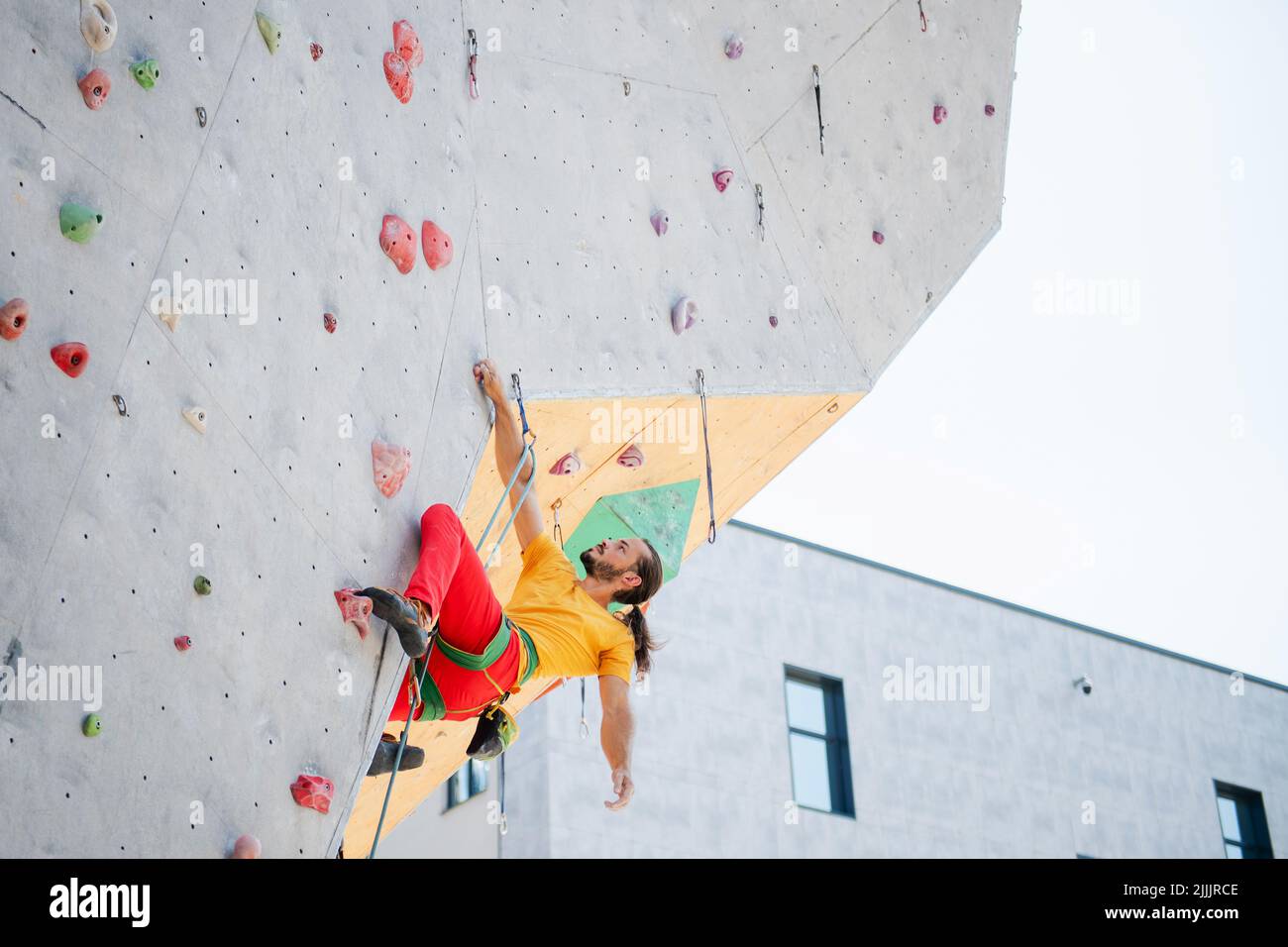 A man climbs up an artificial wall at a climbing wall. Bottom view
