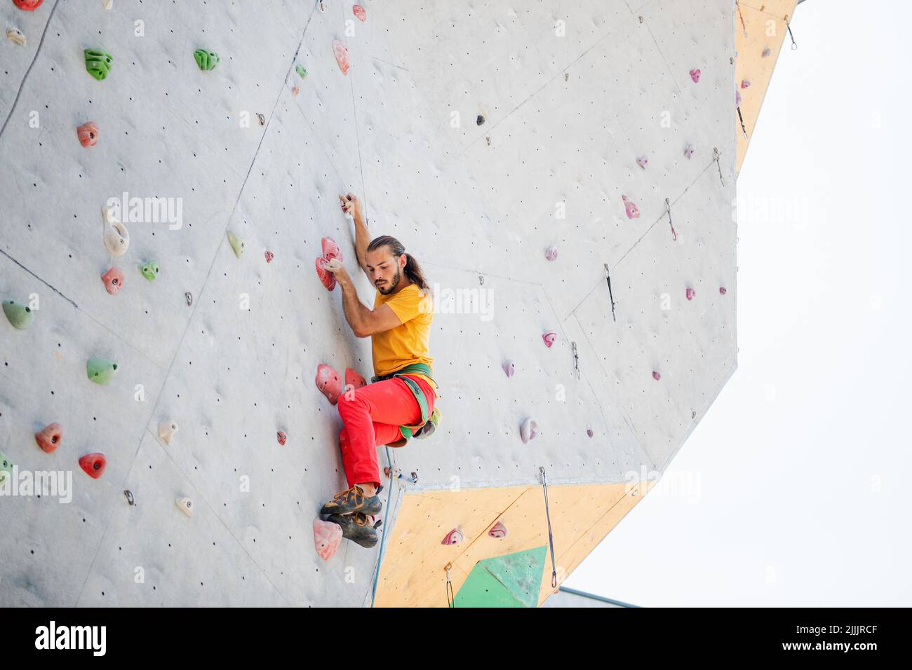 A man climbs up an artificial wall at a climbing wall. Bottom view