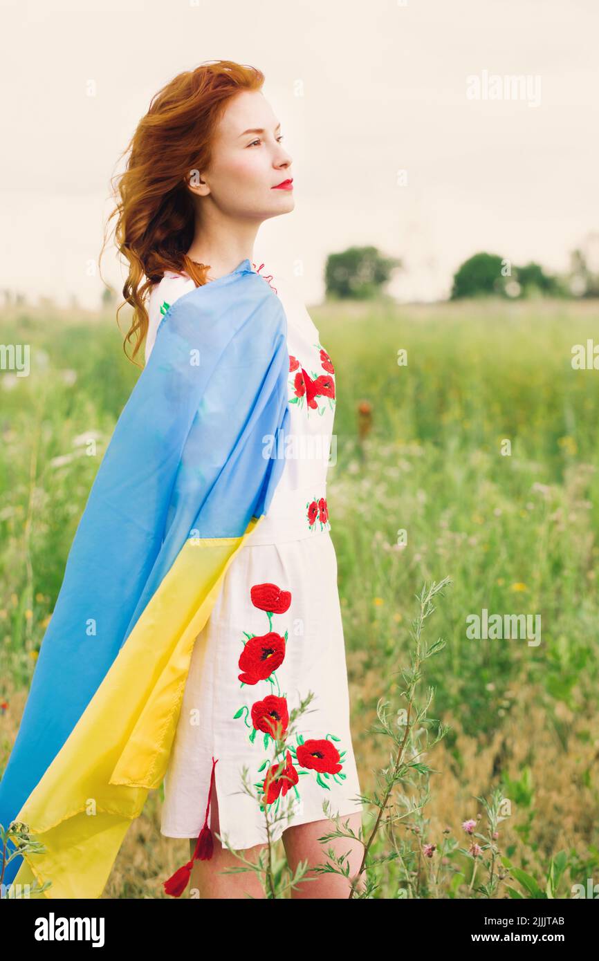 A beautiful Ukrainian woman in a folk dress with a flag of Ukraine is ...