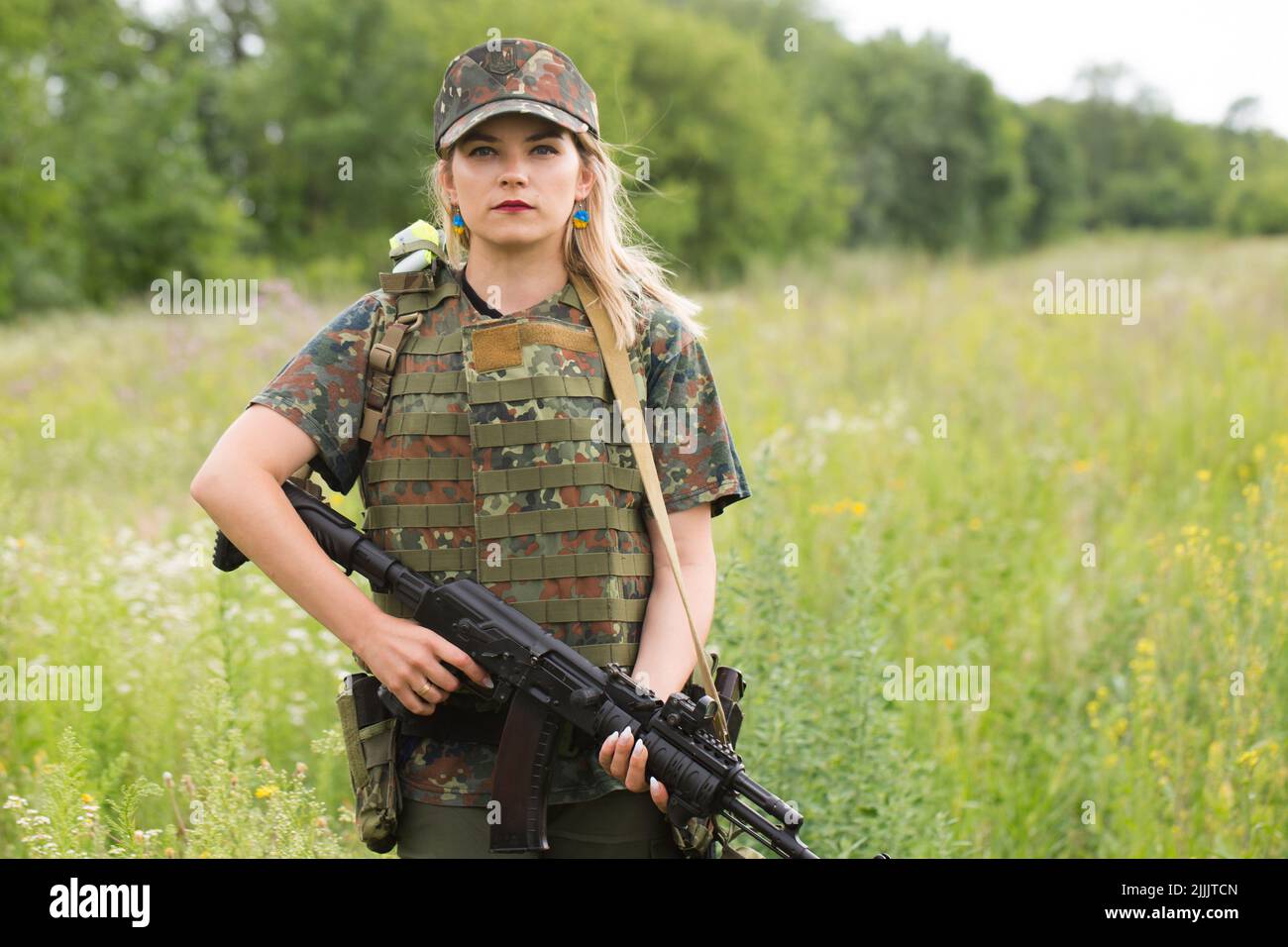 Ukrainian female military servicewoman with a machine gun in her hands in the middle of a field Stock Photo
