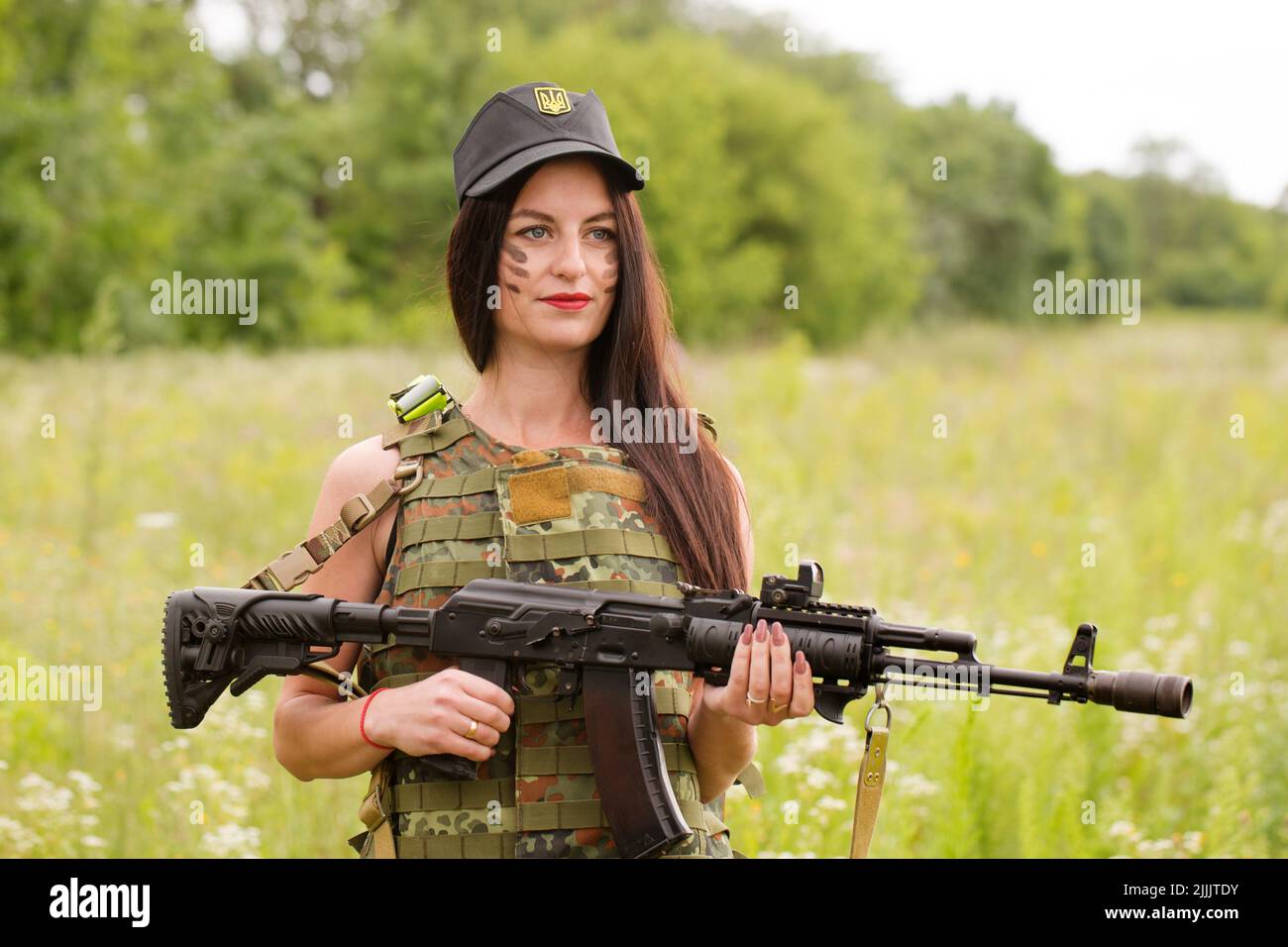 Ukrainian female military servicewoman with a machine gun in her hands in the middle of a field Stock Photo
