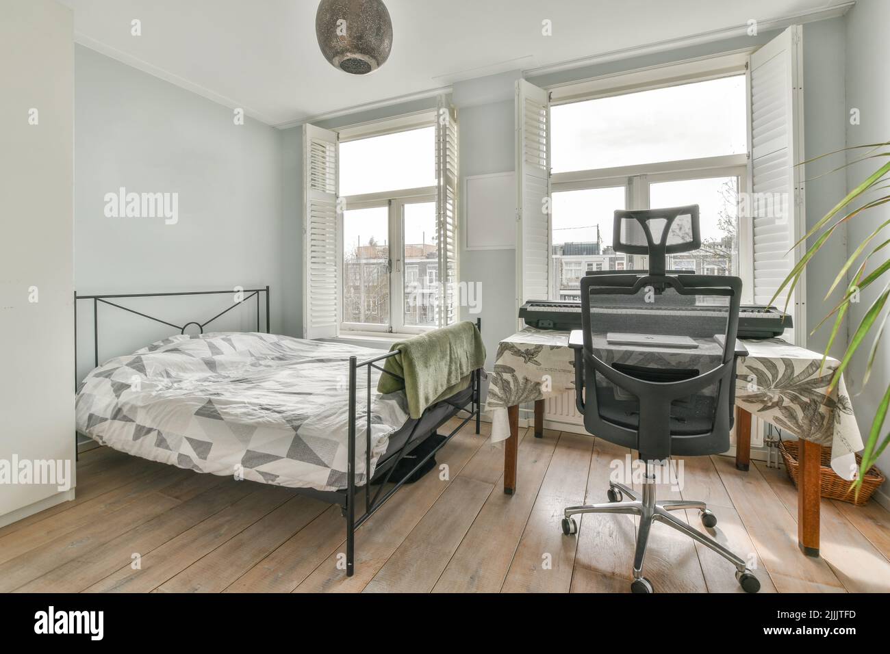 Comfortable bed and lamp placed in small narrow minimalist style bedroom with table under