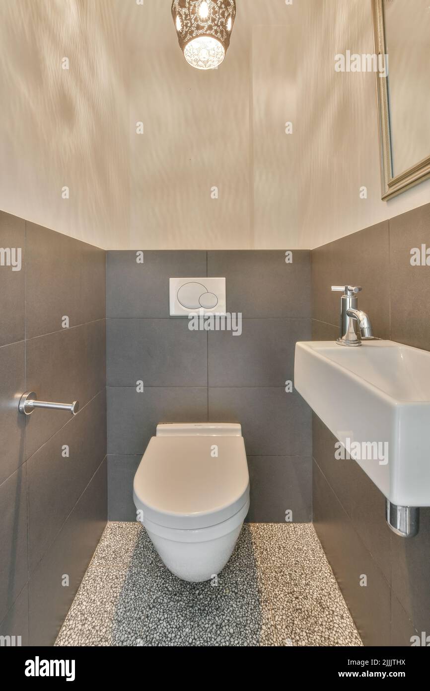 Modern toilet installed on beige wall under button and illuminated
