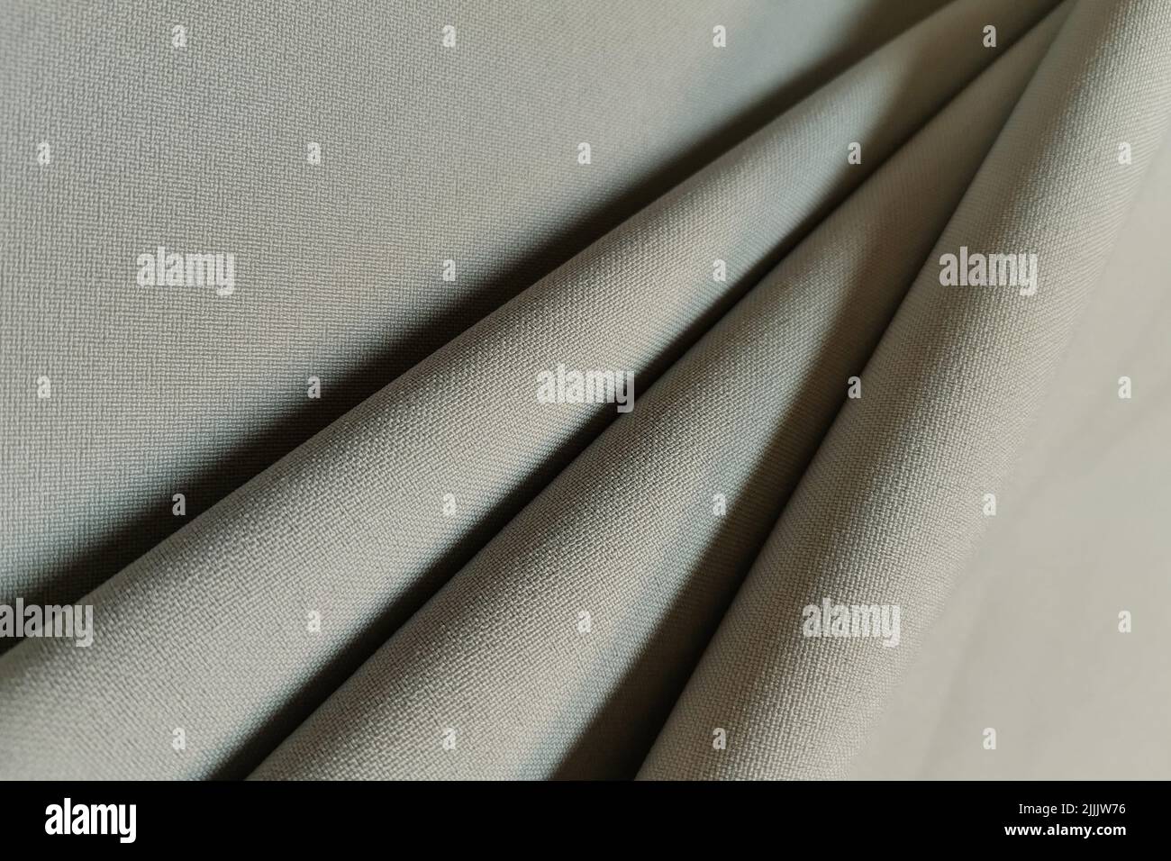 Beige crumpled or wavy fabric texture background. Abstract linen cloth soft waves. Gabardine wool fabric. Merino yarn. Smooth elegant luxury cloth Stock Photo