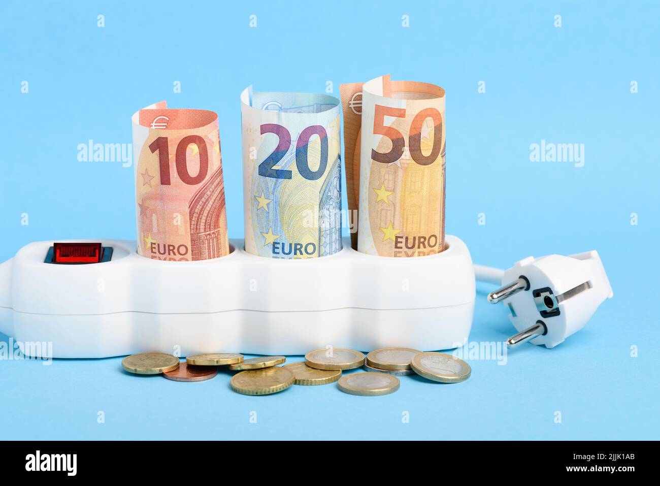 Euro bills in power strip and plug with coins on blue background. Concept of expensive electricity costs in Europe and rise in energy bill prices. Stock Photo
